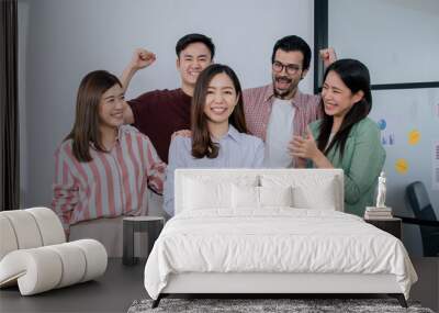 Group of mixed race people wearing casual business shirt, smiling with happiness and success, congrats and give applause to asian female leader. Wall mural