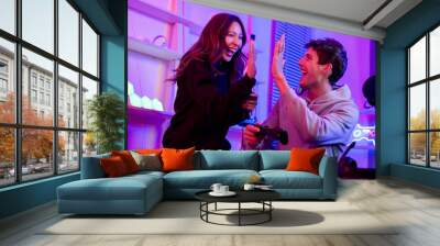 Happy couple or friends smiling with fun, high five for winner, play games together, sitting in room at home with neon decorated light. Game online streamer Concept. Wall mural