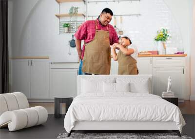 Portrait Asian two people of father with handicap prosthetic leg, little daughter playing, standing in kitchen at cozy home, looking each other, smiling with happiness, love. Family Concept. Wall mural