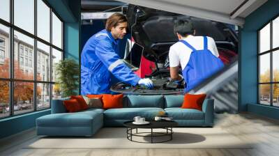 Two handsome male mechanics wearing uniform, using laptop, checking or inspecting for fix, repair car or automobile components, working in car maintenance service center or shop. Industry Concept. Wall mural