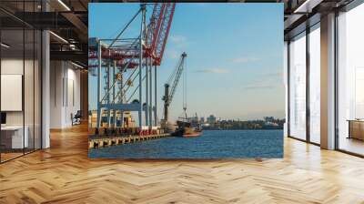 a view of the cargo port and cranes, a ship with containers at the pier. sunny day, calm water of th Wall mural