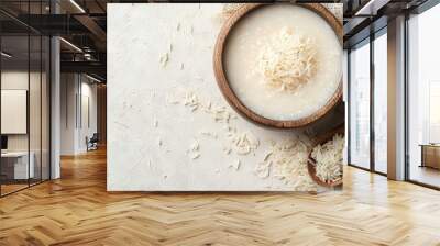   A bowl of rice next to a wooden spoon on a white surface Wall mural