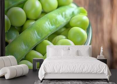   A glass bowl filled with peas sits atop a wooden table alongside a piece of green fruit Wall mural