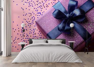   A purple present package with blue decorations on a pink backdrop, featuring blue and purple decorations Wall mural