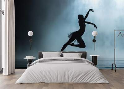  a silhouette of a ballerina dancing in front of a waterfall with her arms in the air and her leg in the air, with her right leg in the air. Wall mural