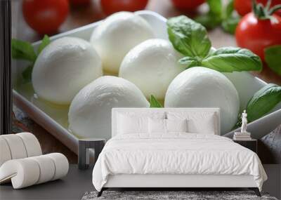   A wooden table holds a mozzarella plate with juicy tomatoes and fresh green leaves on the edge Wall mural