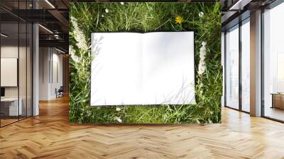 The open album lies on green grass in the park. White sheet on lawn, free space for your design, mock up Wall mural