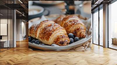  Two croissants sit on a plate with blueberries in front of a cup of coffee Wall mural