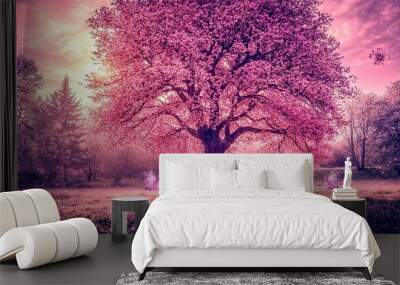  Two girls play under a giant, rosy tree, surrounded by a serene pink sky Wall mural