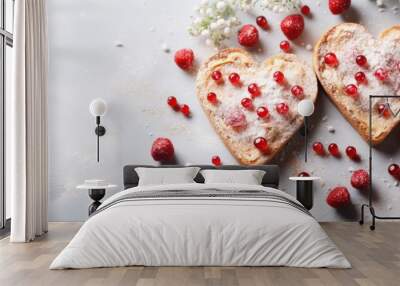  two heart shaped pieces of bread covered in powdered sugar and raspberries on top of a white surface. Wall mural