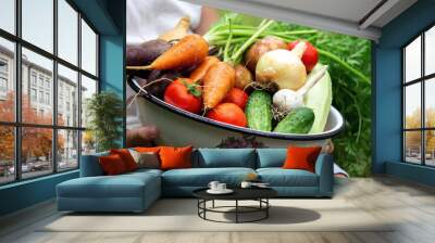 a child holding a bowl of freshly picked vegetables on a farm. Wall mural