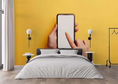 A hand is holding a smartphone with a blank screen against a vibrant yellow background, tapping the screen with one finger. Wall mural