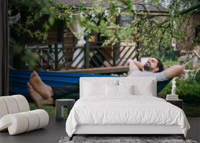 A man is resting in a hammock in a country house Wall mural