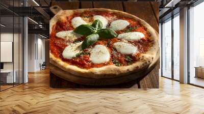 A Margherita pizza topped with melted mozzarella cheese and fresh basil leaves, baked to a golden brown crust, served on a wooden surface, captured in a top-down view. Wall mural