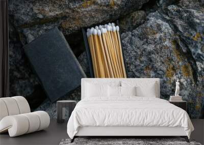 A top-down view of a pack of waterproof matches resting on a rocky surface, with a striking pad nearby. The focus is on the matches' packaging and design. Wall mural