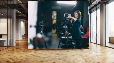 A young female director of photography at work behind a movie camera on a film set for a movie, commercial or broadcast Wall mural