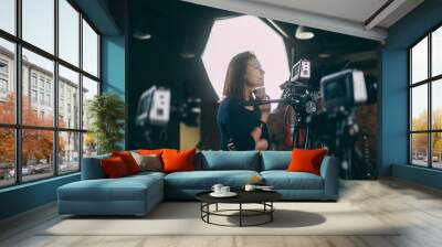 A young female director of photography at work behind a movie camera on a film set for a movie, commercial or broadcast Wall mural