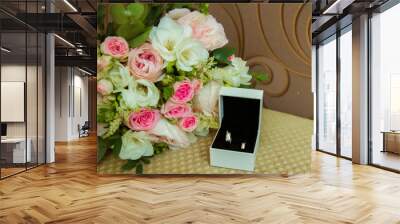 Wedding ring in white gold. Two platinum rings of the bride and groom in a white box and a bouquet of pink roses and white flowers Wall mural