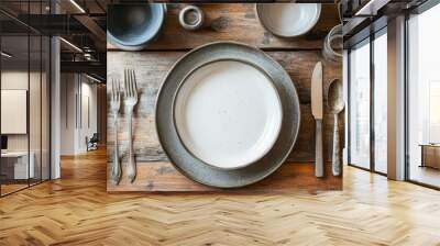 Artistic shot of handcrafted ceramic dinnerware, arranged alongside vintage cutlery on a wooden table, highlighting artisanal table settings. Wall mural