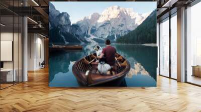 man and dog in a boat on a mountain lake. Trip with a pet to Italy. Australian Shepherd Dog and its owner Wall mural