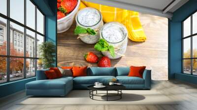 Two glasses of natural yogurt with chia on a wooden table are decorated with mint and strawberries. Wall mural