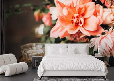 close-up of a burning candle in a floral arrangement on a vintage delivery on a background a decorated festive table with a blue tablecloth on the background of a wooden wall Wall mural