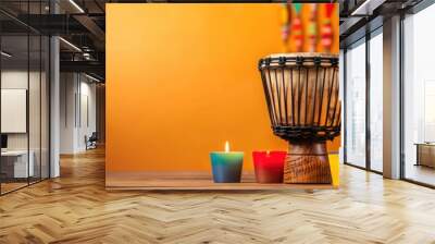 Colorful candles and African djembe drum against vibrant orange background. Wall mural