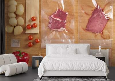 Delivery set of packaged food for dinner. meat in plactic bag and vegetables: potatoes, onions, spices, cherry tomatoes, red pepper on wooden table background Wall mural