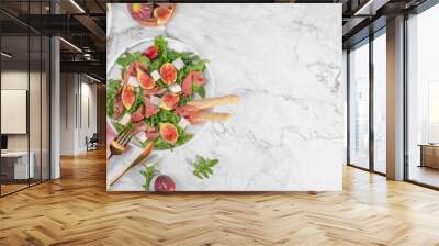 Autumn figs salad with arugula, feta, raw ham in two white plate on light marlbe background served with rose wine. Flexitarian diet, paleo diet fall or summer salad, top view, flat lay, copy space Wall mural