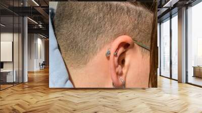 Head with teenage hairstyle, ear close-up with earring and piercing. Teenage style Wall mural