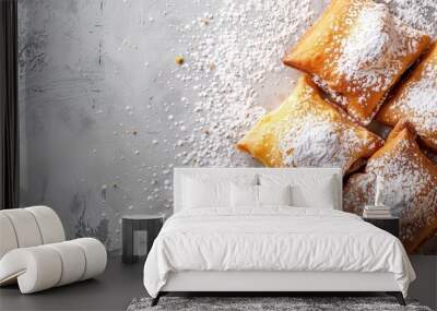 Four powdered sugar beignets de banane on a textured gray background with scattered sugar. Confectionery, pastries, French cuisine, bakery products, dessert presentation, food photography. Wall mural