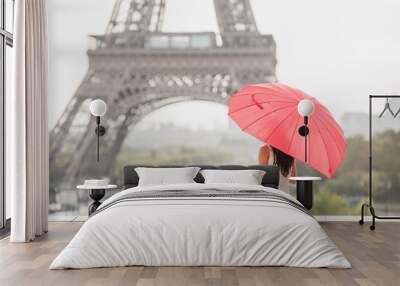 Girl hiding herself behind heart shaped red umbrella in front of the Eiffel tower Wall mural