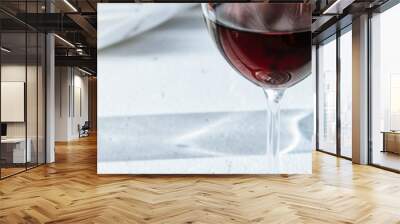 Glass of red wine in front of a white wall at a vineyard on a bright sunny summer day Wall mural