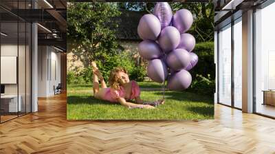 happy beautiful tender girl 17-18 years old with bunch of purple helium balloons lies on green lawn. Birthday girl. Happy day. concept of joy, positivity and congratulations. Dreams, festive mood Wall mural