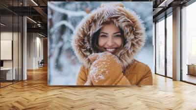 Happy woman smiles and wraps herself in warm clothes in winter forest on snow background Wall mural