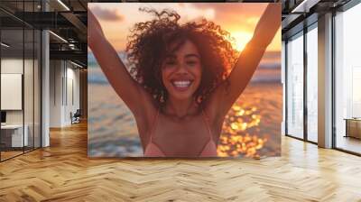 Joyful woman with curly hair enjoying a beach sunset, with arms raised and smiling brightly. ai generative Wall mural