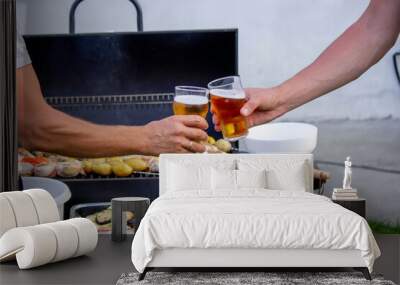 men hold beer in their hands on the background of the grill, vegetables and meat. Selective focus. Wall mural