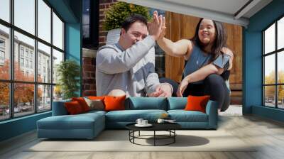 Young biracial couple with Down Syndrome in active wear and wearable tech high-fiving Wall mural