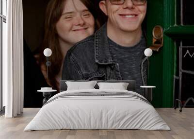 Young couple with Down Syndrome and Foetal Alcohol Syndrome standing at front door and smiling Wall mural