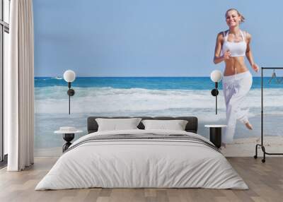 Healthy woman running on the beach Wall mural