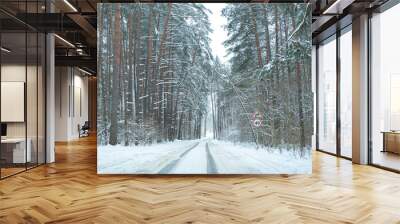 Winter road snowfall. An empty rural road without cars, covered with snowdrifts. Travel in bad weather. Winter cloudy landscape with a country road. Tracks of passing cars. The concept of winter magic Wall mural