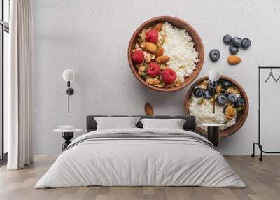 Two different Cottage cheese bowl with blueberries and raspberries, granola, almonds, walnuts and honey. Servings of healthy breakfast on light gray background Wall mural