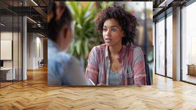 Serious young woman in a professional setting, deep in conversation, focusing on the discussion. Wall mural