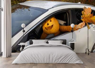 smiling halloween pumpkin driving a white car. Vacation, humor, vehicle, car part, holiday delivery. Have fun on Halloween by going to a party Wall mural