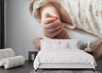 The newborn clings tightly to his father's finger. Close-up of the small hand of the child and the hand of the parent. The concept of education, child care and healthcare. Paternity. Family Wall mural