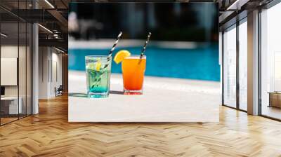 Tropical sparkling lemonade cocktails by the pool. Glasses with orange and mint lemon fruit cocktails. Summer alcohol free drink by the hotel pool. Hello summer holiday vacation Wall mural