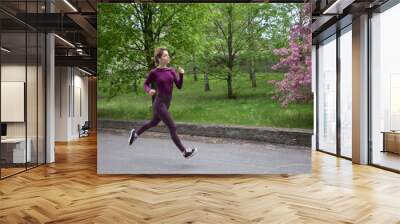 young slender woman runs along the forest. Exercise with health benefits. Teenage girl on the move, jogging. energy of nature, freedom. healthy active lifestyle Wall mural