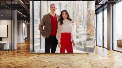 Fashion style Clothes, business casual. Respectable Businessman Wearing brown jacket and sweater and Woman in red pants and a stylish white shirt looking at camera and smiling Wall mural