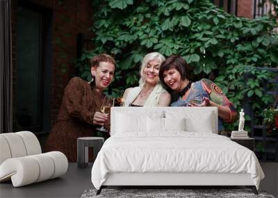 Mature women celebrate and laughing, hold sparklers and clink glasses of alcohol wine or champagne on outdoor party Wall mural