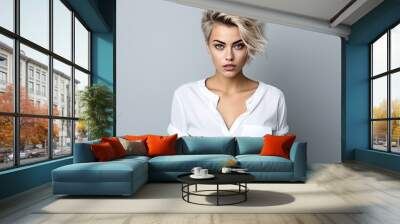 Portrait of a stylish young blonde woman with short hair, confidently gazing into the camera against white studio background Wall mural